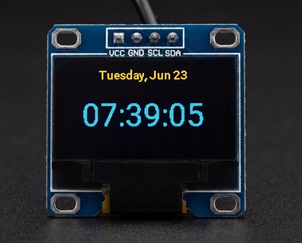 Shot of a 0.96 inch SSD1306 OLED display with yellow and blue text displaying Tuesday, June 23 and time 07:39:05 on a black background.